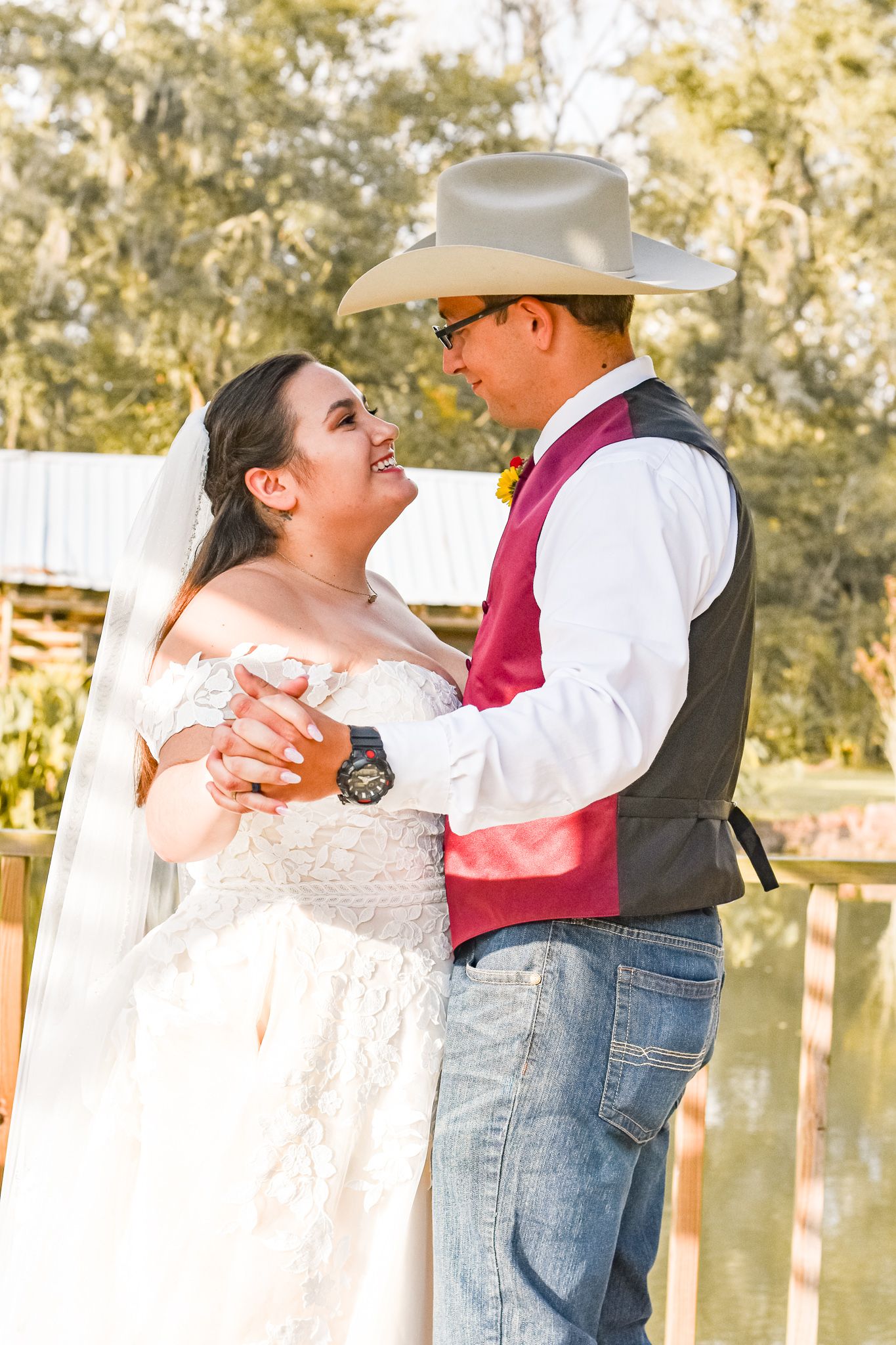 A wedding couple shares a romantic dance moment on a lakeside dock at sunset.