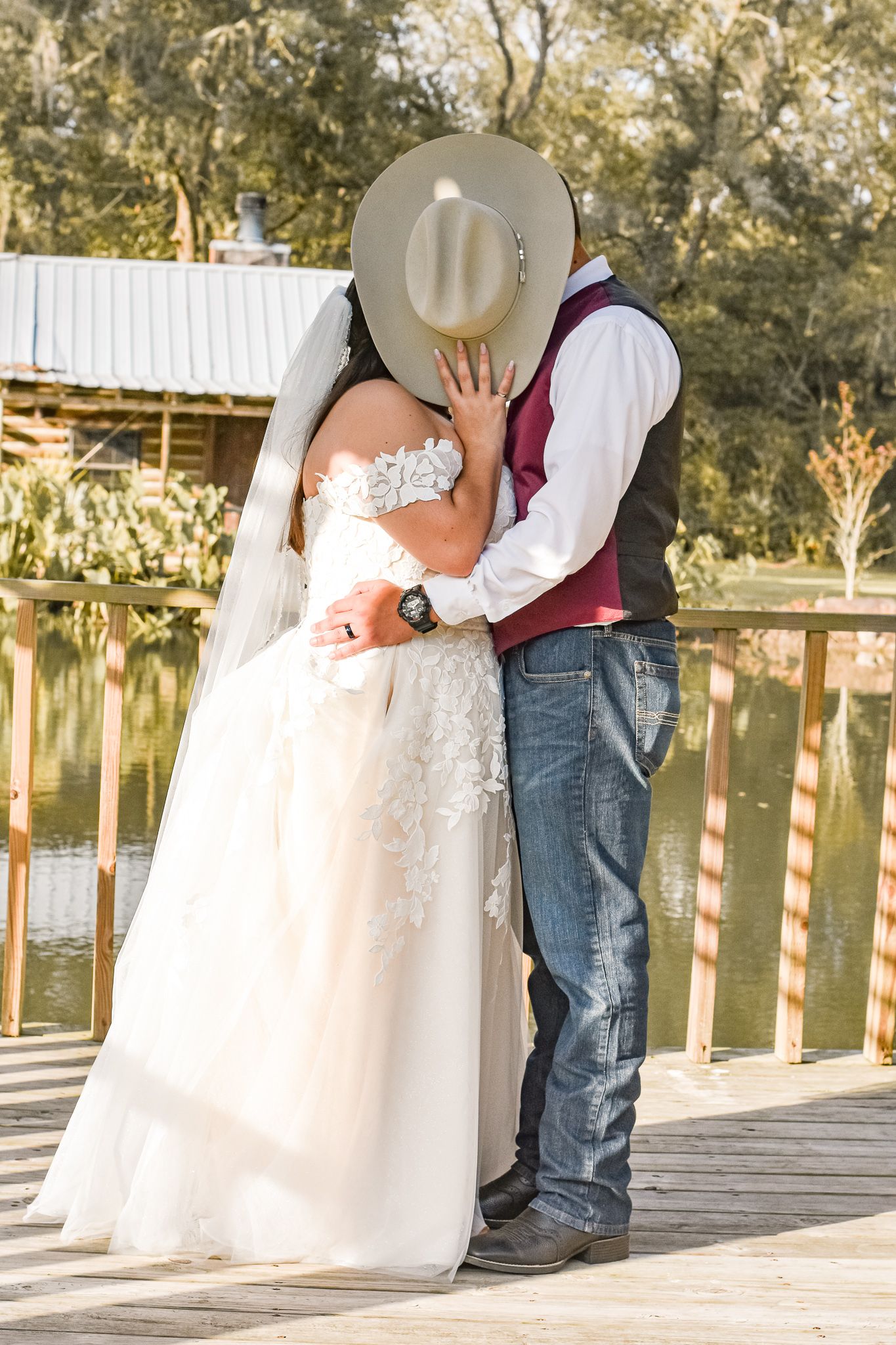 Romantic wedding moment shared between couple on a wooden dock overlooking water.