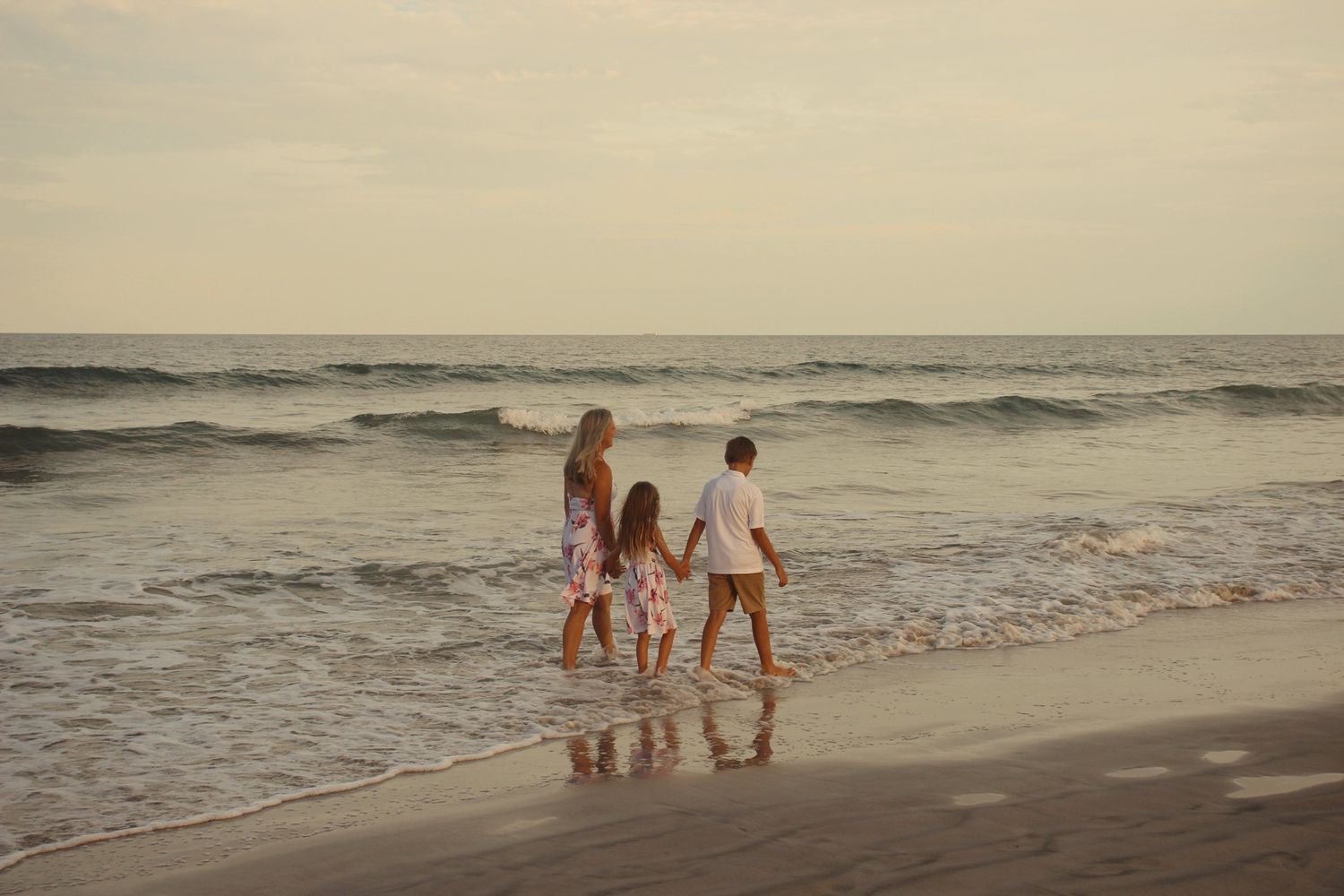 family walking away at sunset on the beach, waves behind