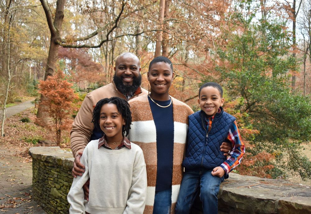 Group posed together outdoors with fall foliage in background.