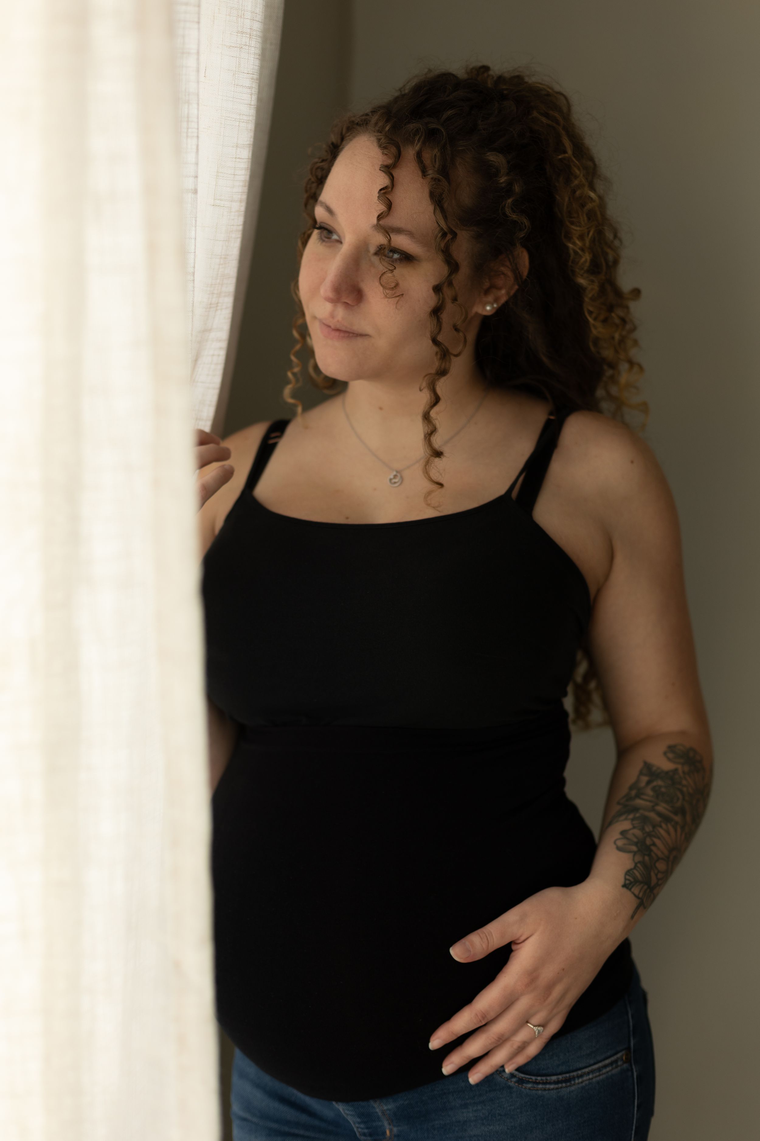 A pregnant mom peaking out the curtains of her Charleston, Illinois home.