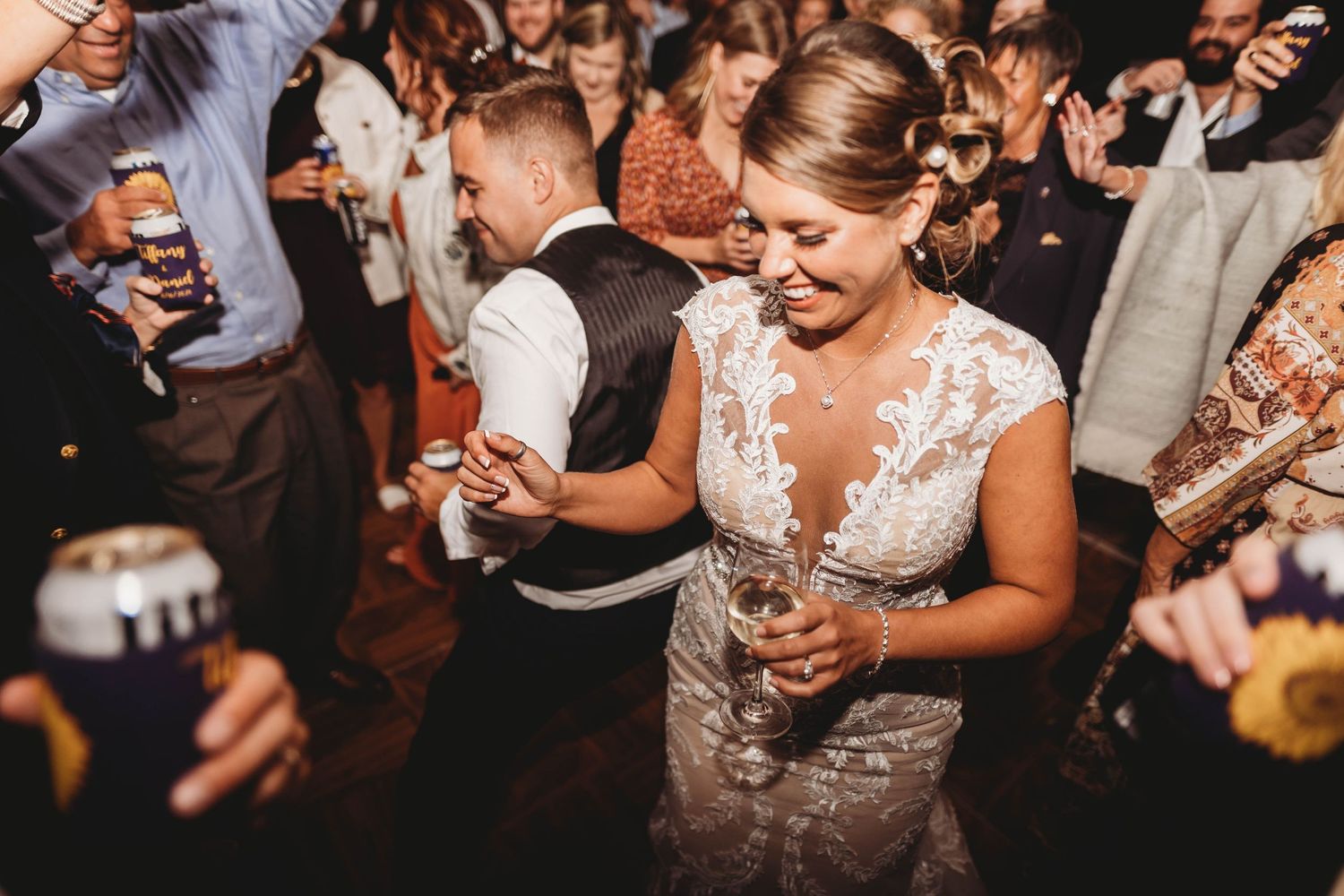 Wedding reception dance party with crowd celebrating on dance floor.