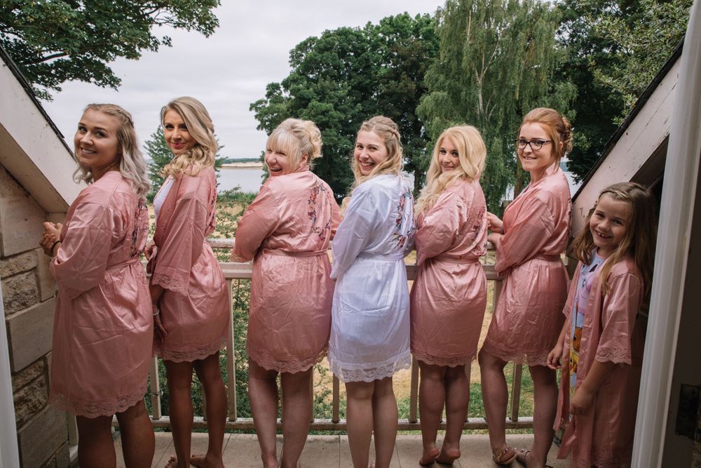 Group wearing matching pink and grey robes stand in a line with backs turned to camera.