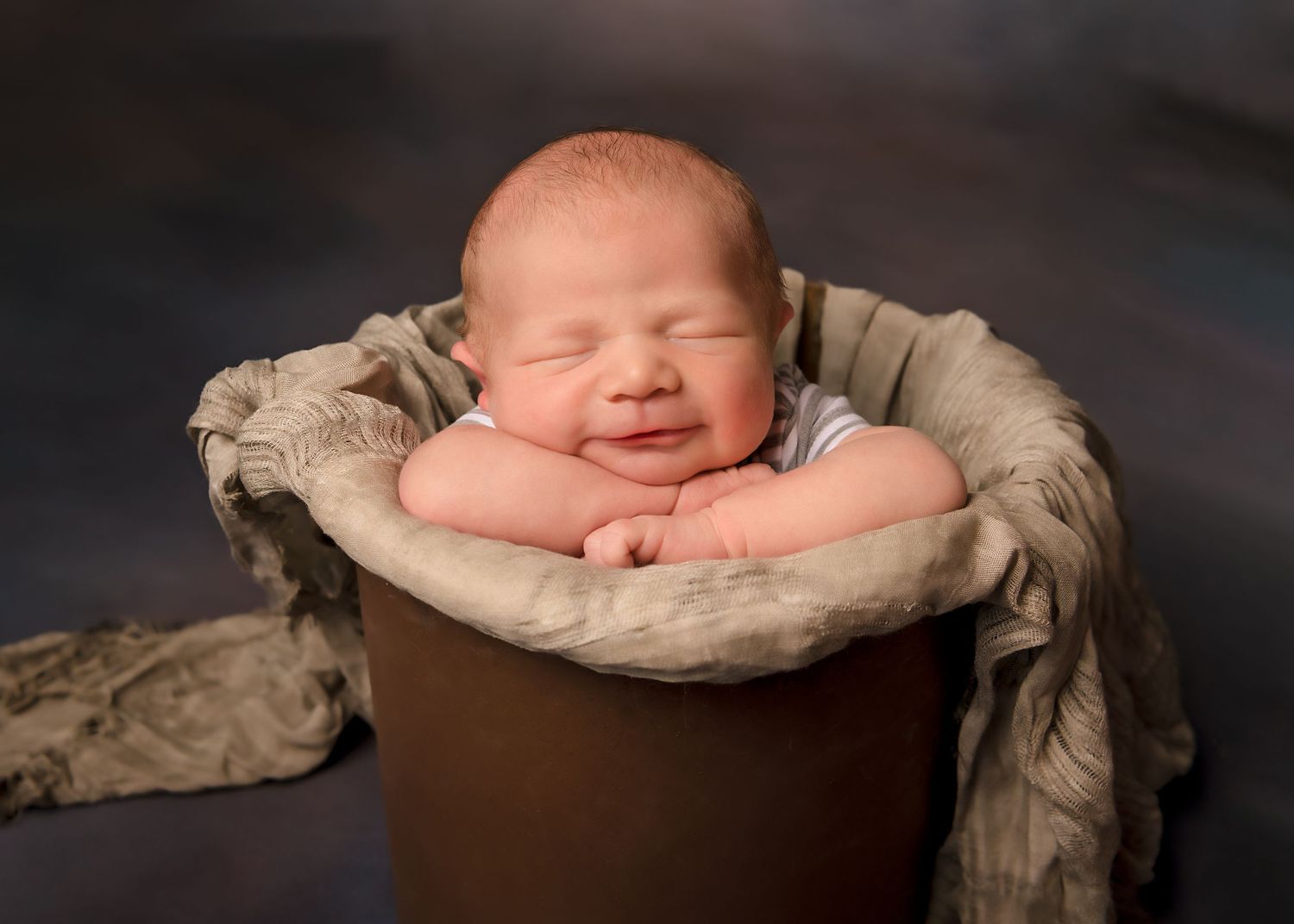 smiling newborn baby boy in rust colored bucket