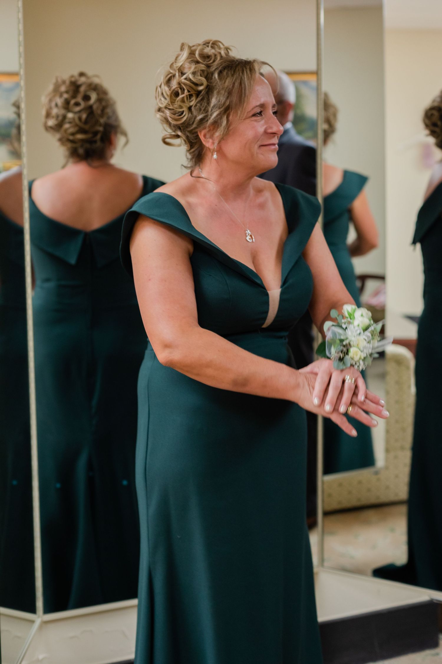 Bridesmaid in dark green dress shares emotional moment at wedding.