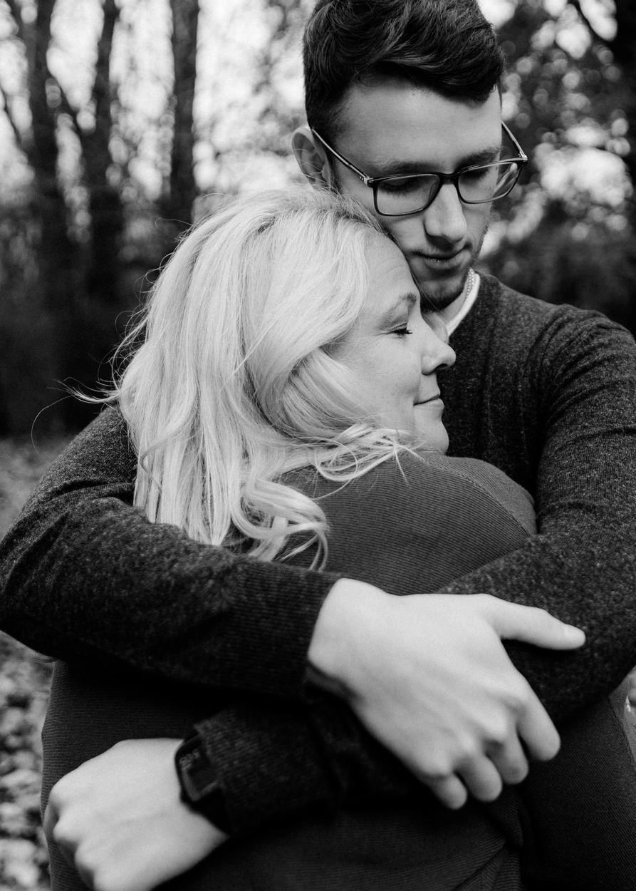 Intimate black and white portrait of couple embracing in a forest setting.