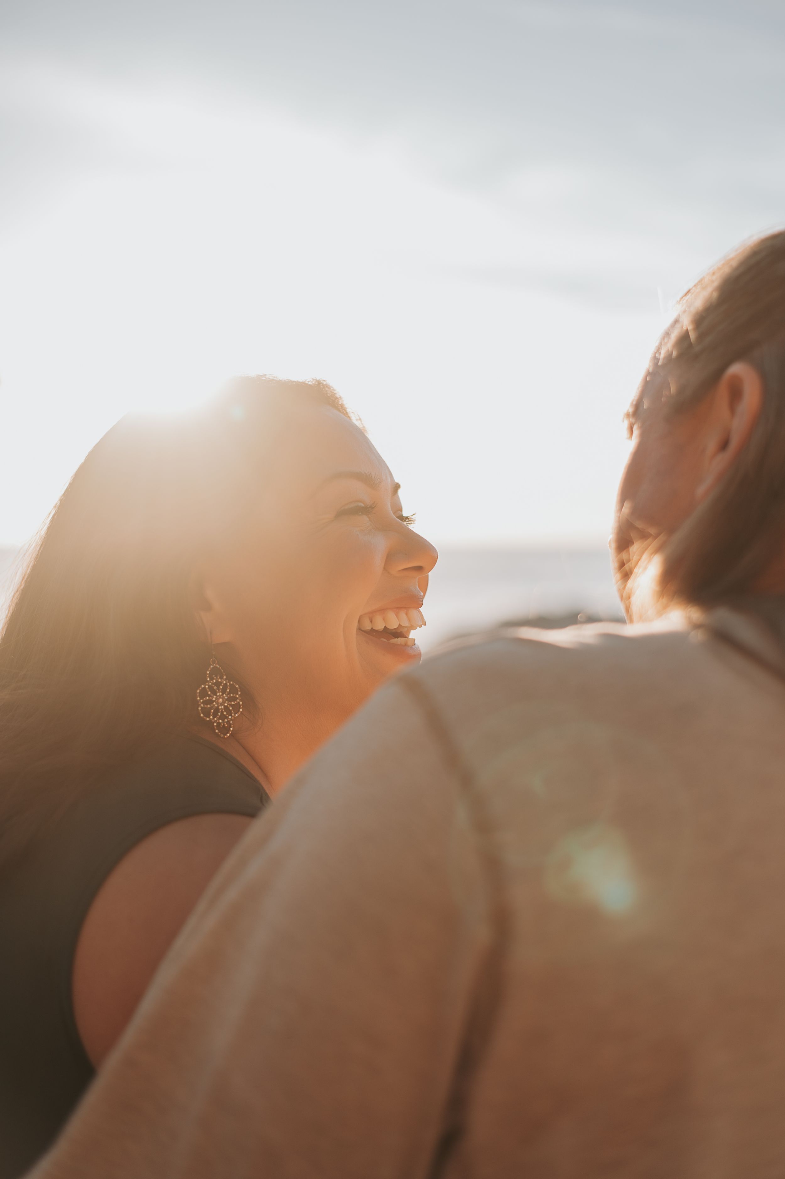 Candid golden hour portrait of a couple laughing together outdoors.