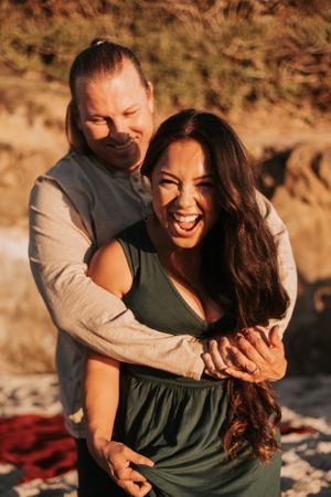 Joyful couple sharing a playful moment on the beach during golden hour.