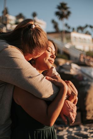 Intimate embrace captured during sunset with palm trees in the background.