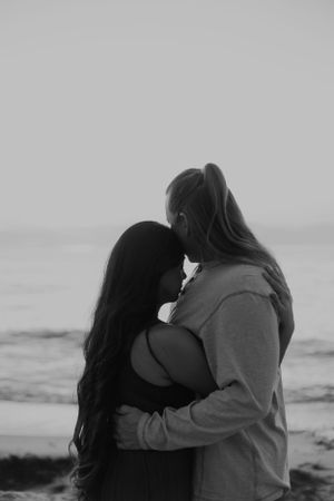 Black and white intimate portrait of a couple embracing on the beach.