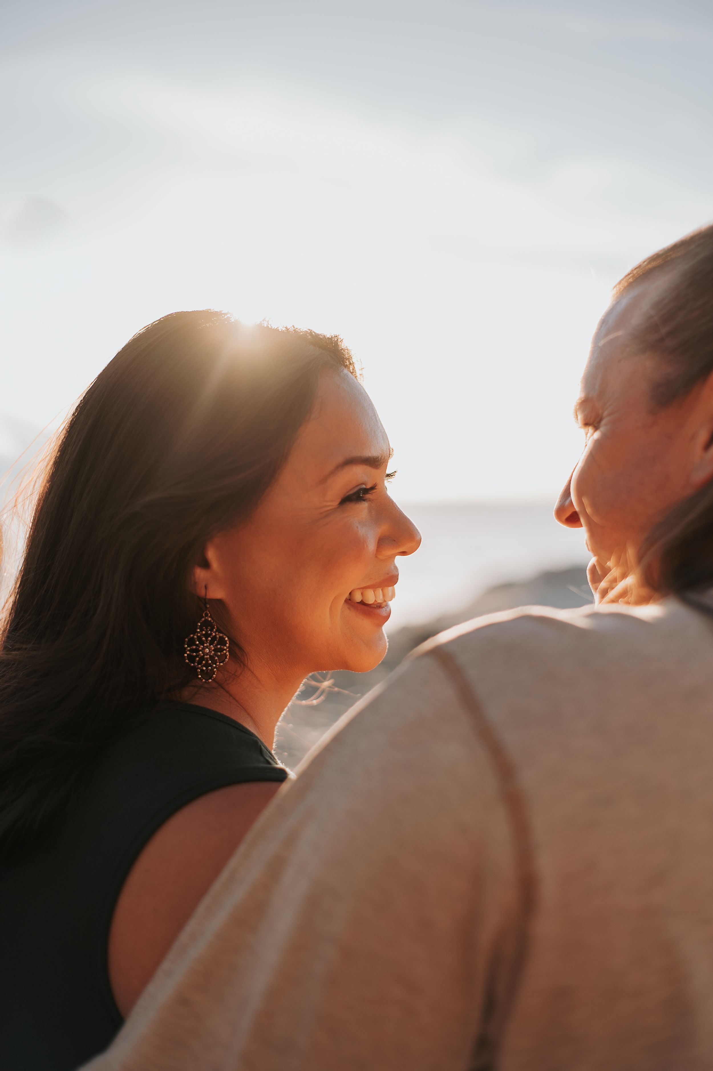 A romantic sunset moment captured between a couple sharing laughter on a beach.