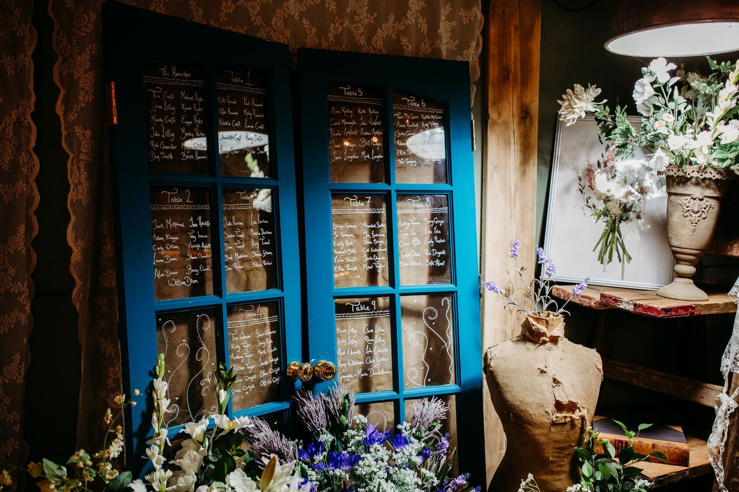 Blue wooden doors with vintage decor and purple flowers against a textured wall create a rustic scene.