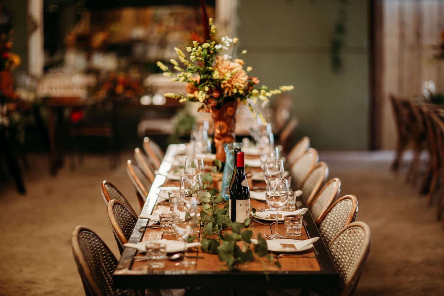 An elegant long dining table set for a wedding reception with floral centerpieces and place settings.