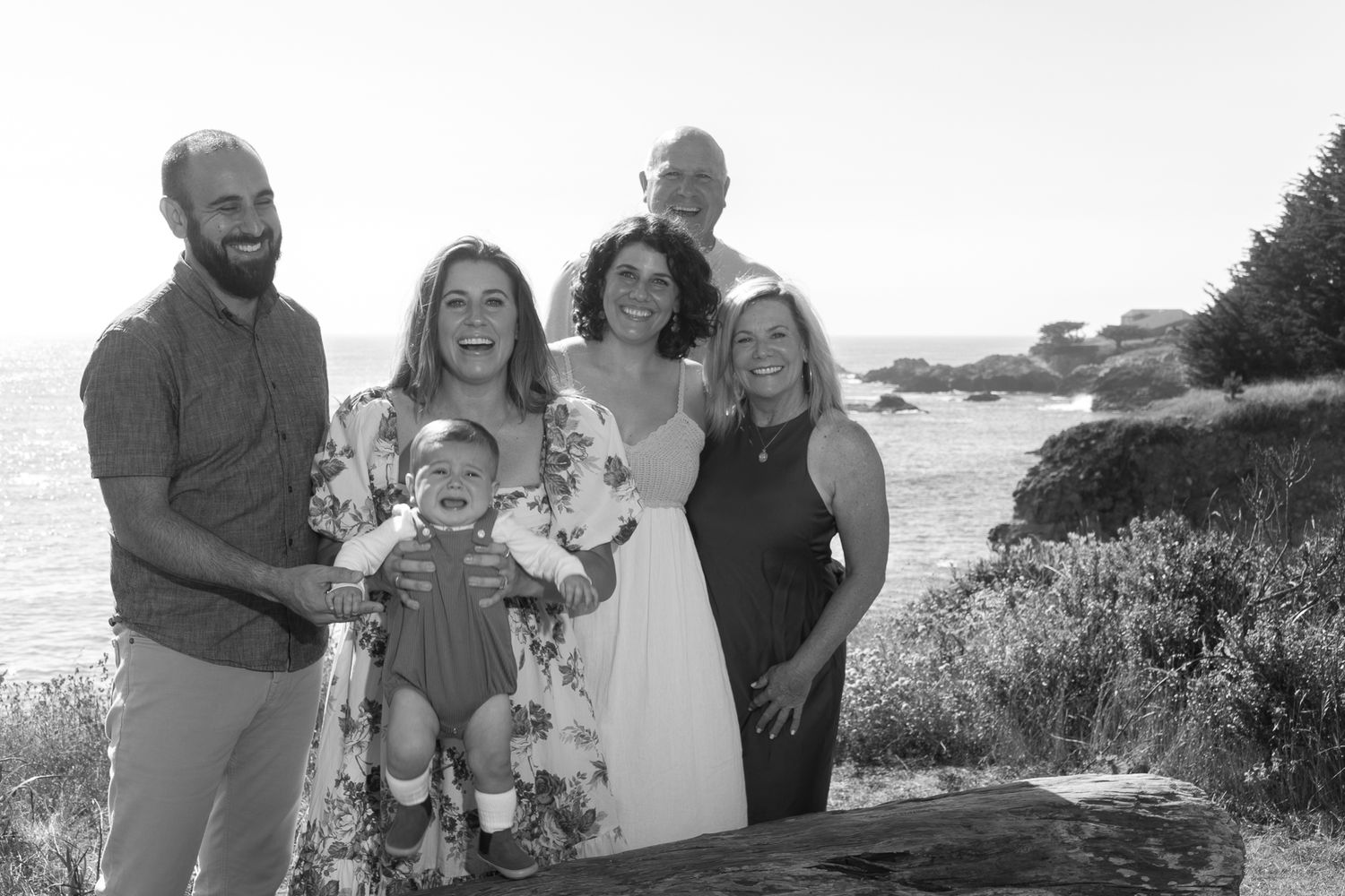 Family group portrait on coastal cliffs during sunset.