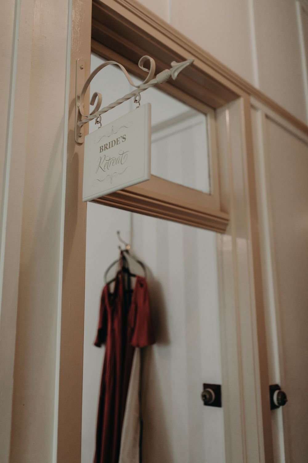 Elegant wooden doorframe with hanging garments visible in soft lighting.