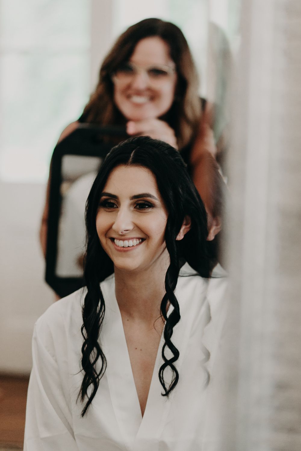 Getting ready photo of a bride in a white robe during wedding preparations.