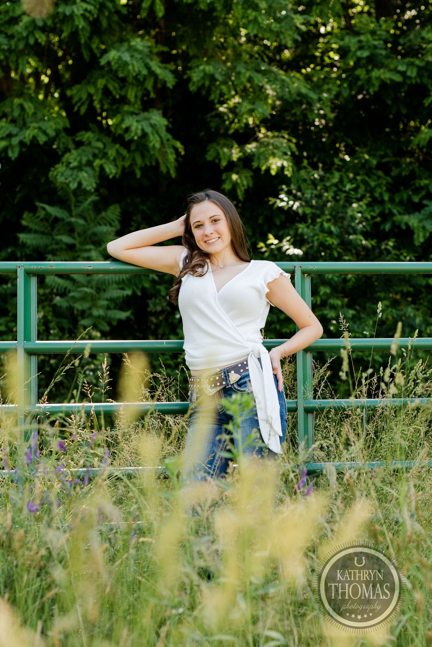 A summer portrait with natural poses against a leafy green background and metal railing.