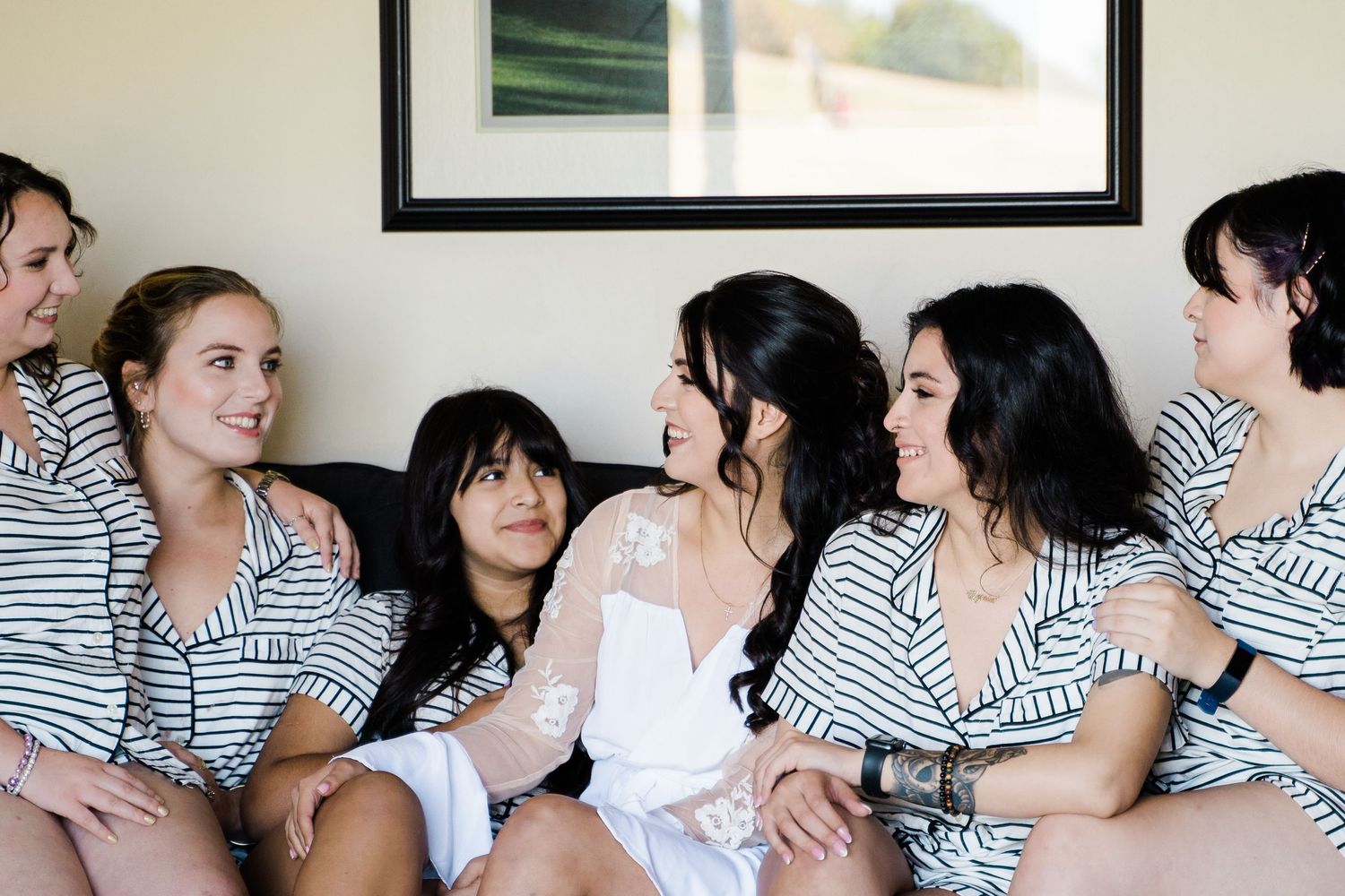 Wedding party in matching striped robes sharing a laugh during pre-ceremony preparations.