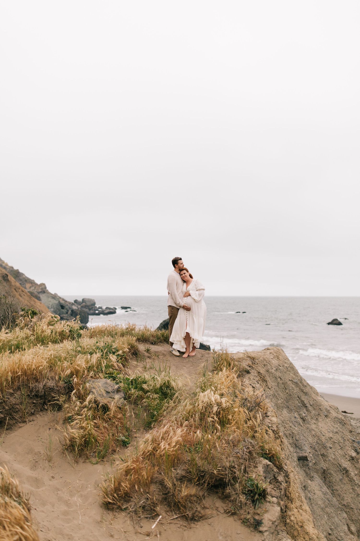 Romantic moment captured on a clifftop overlooking a dramatic coastline.