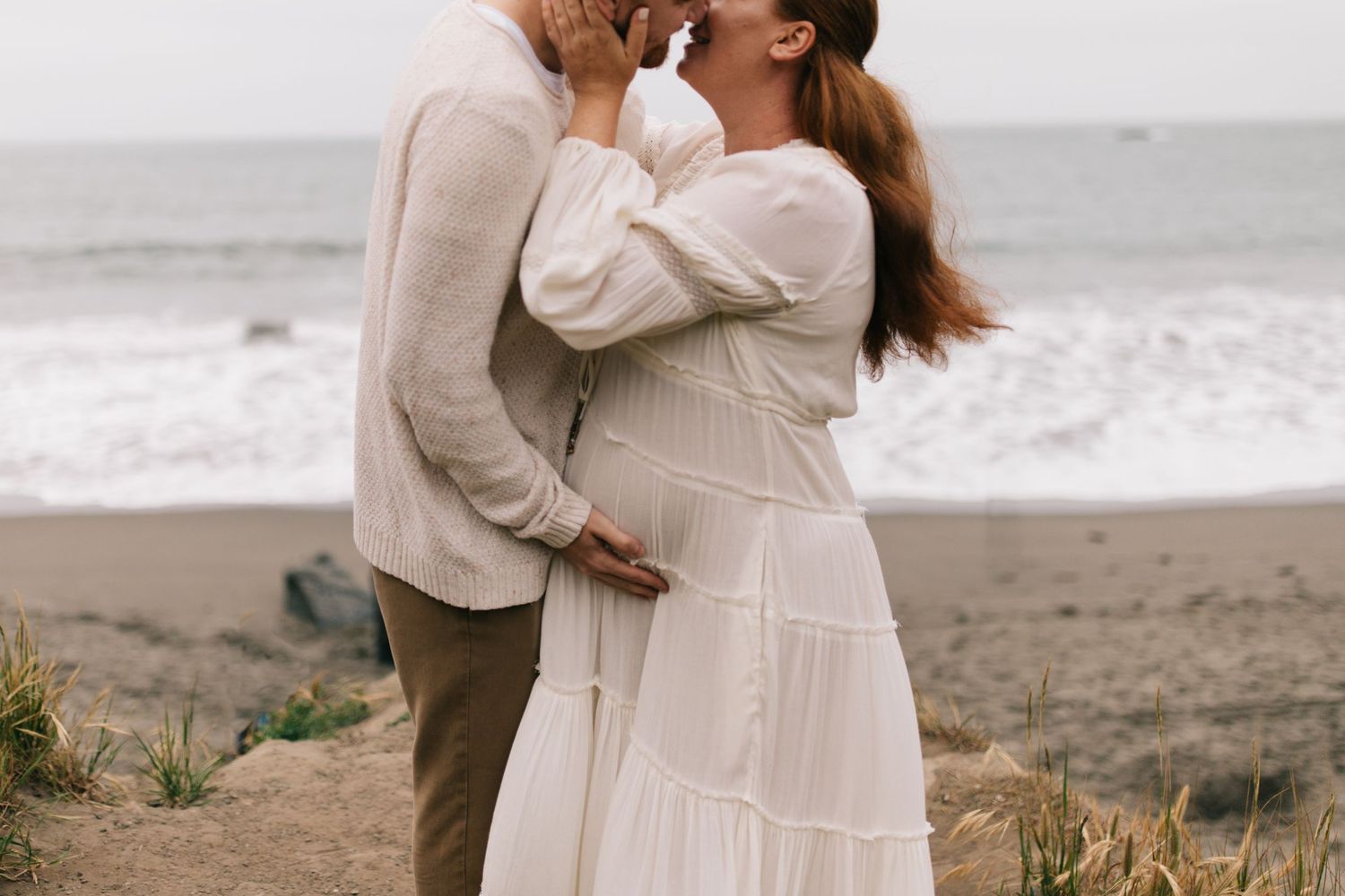 Intimate embrace on a beach with crashing waves in the background.