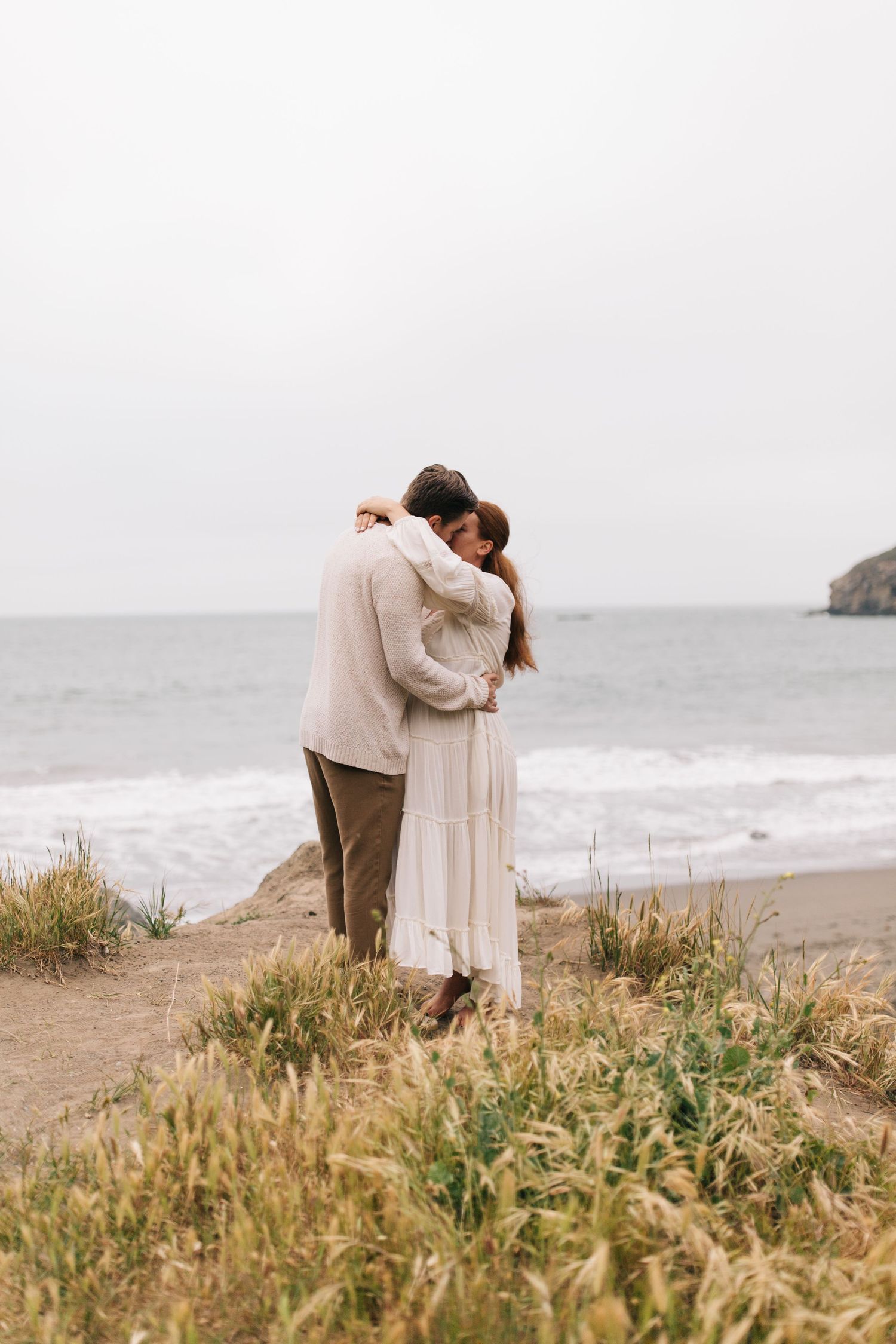 Intimate moment shared on a scenic coastal overlook.