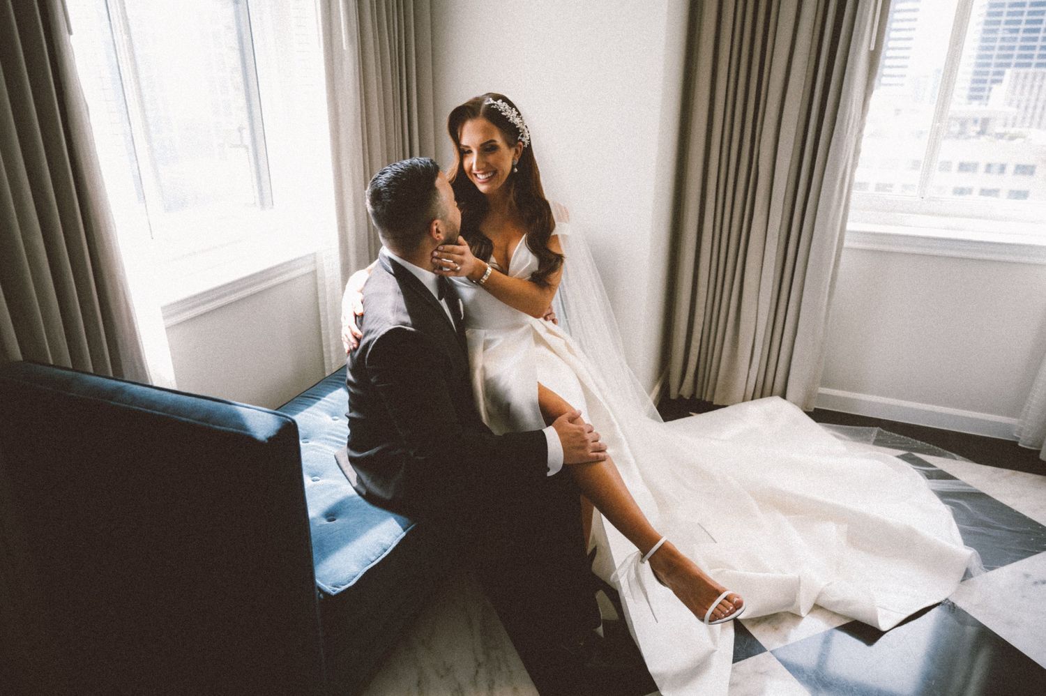 A tender moment shared on a blue velvet couch in a bright room.