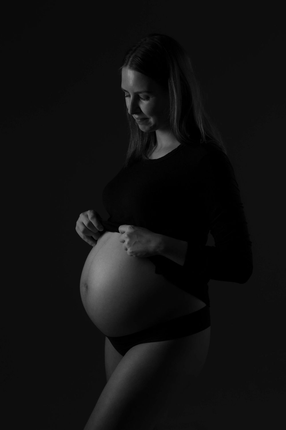 Moody black and white side profile maternity photo.