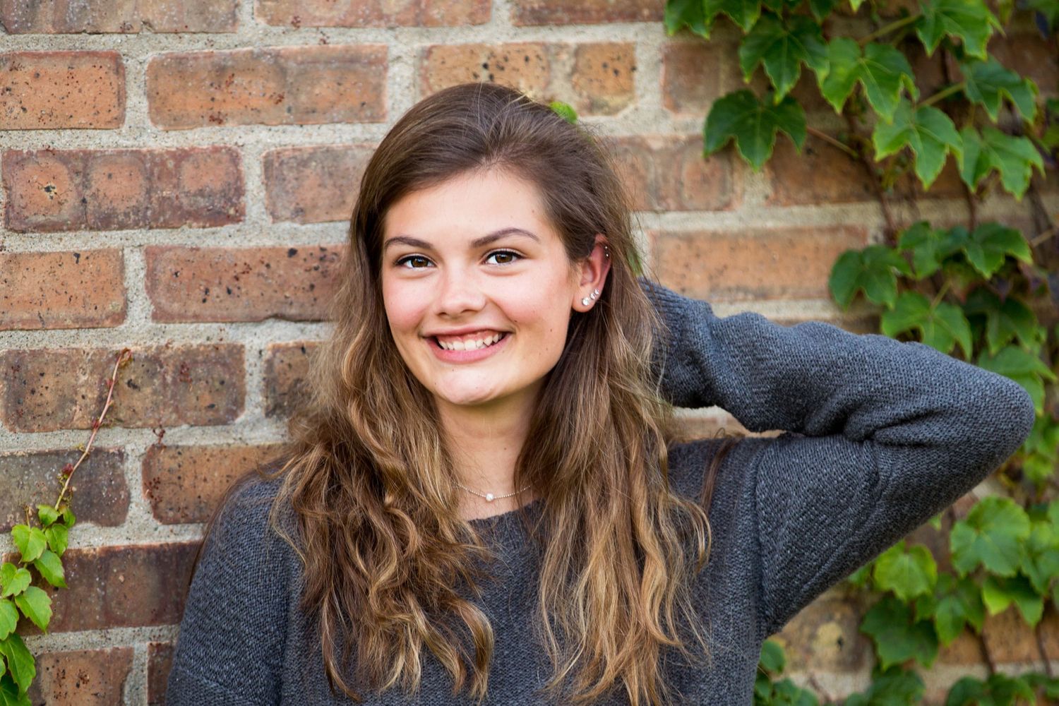 Portrait series against brick wall with ivy showing various expressions.