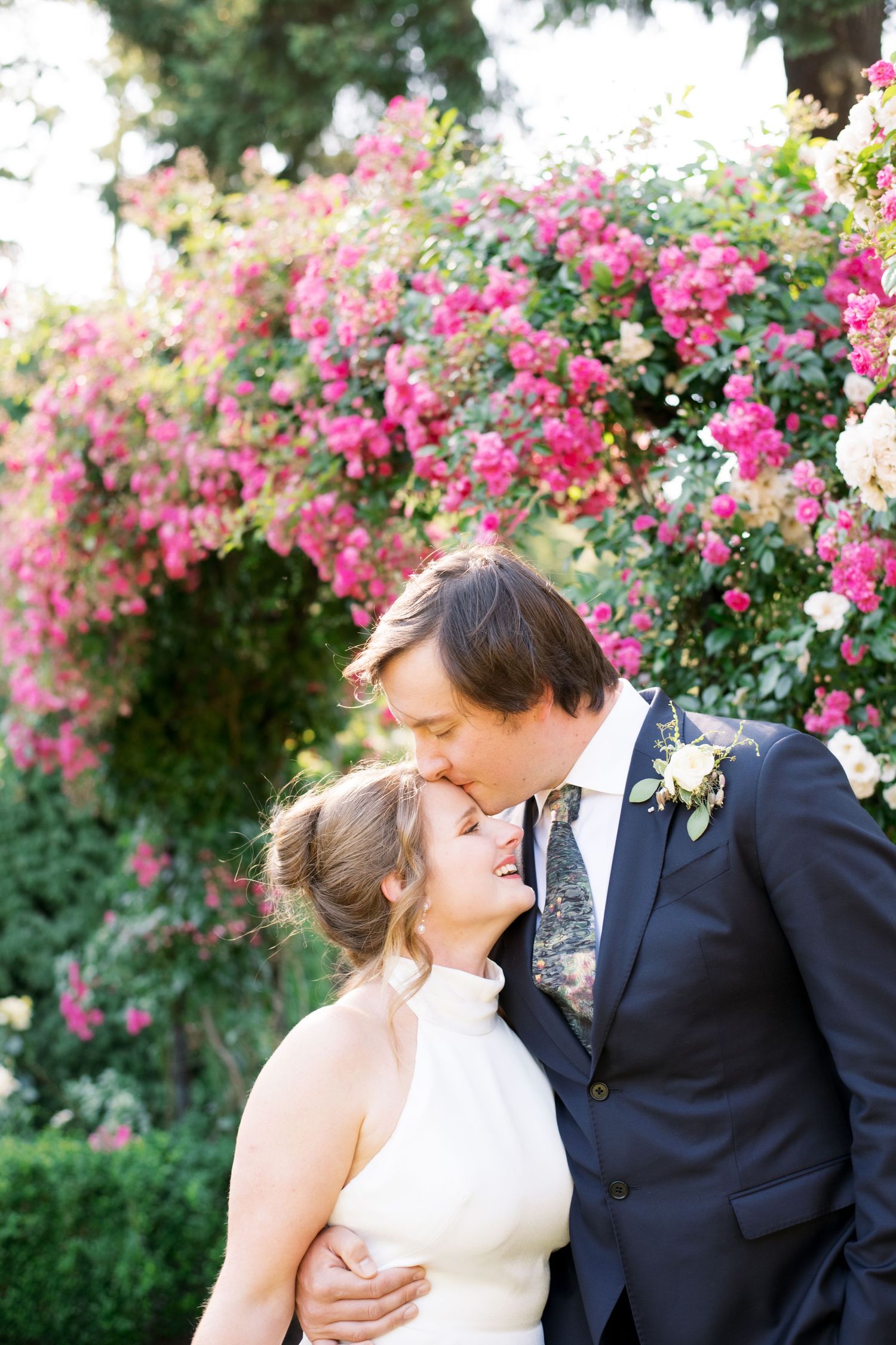 A romantic wedding moment in a garden with blooming pink roses as the backdrop.