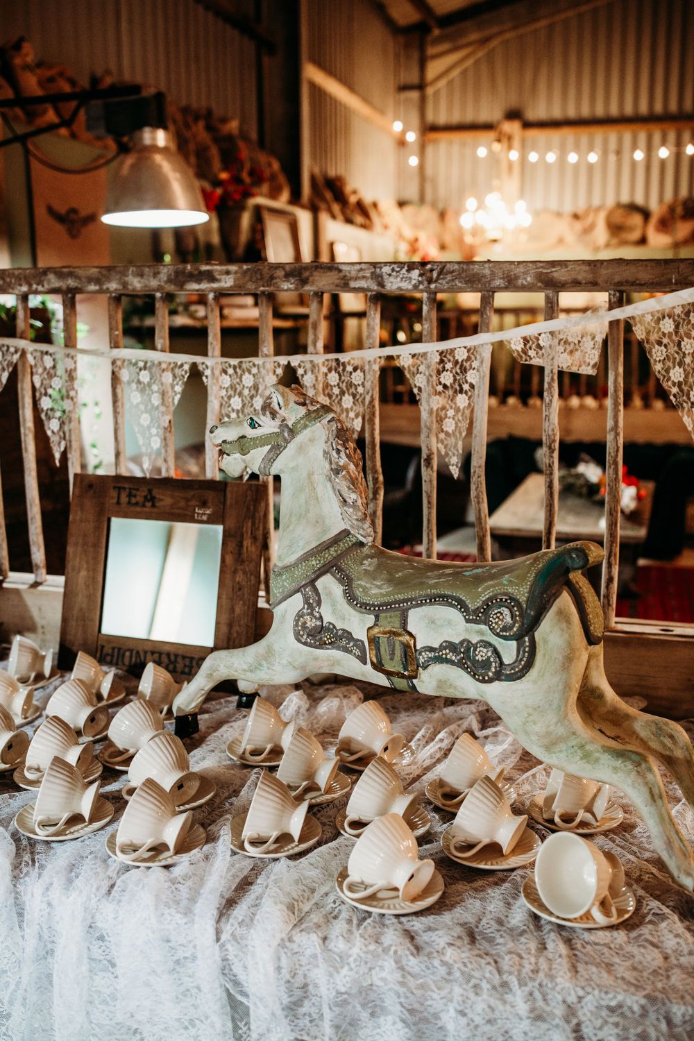 Vintage-style dessert display with lace bunting and decorative teacups on white linens.