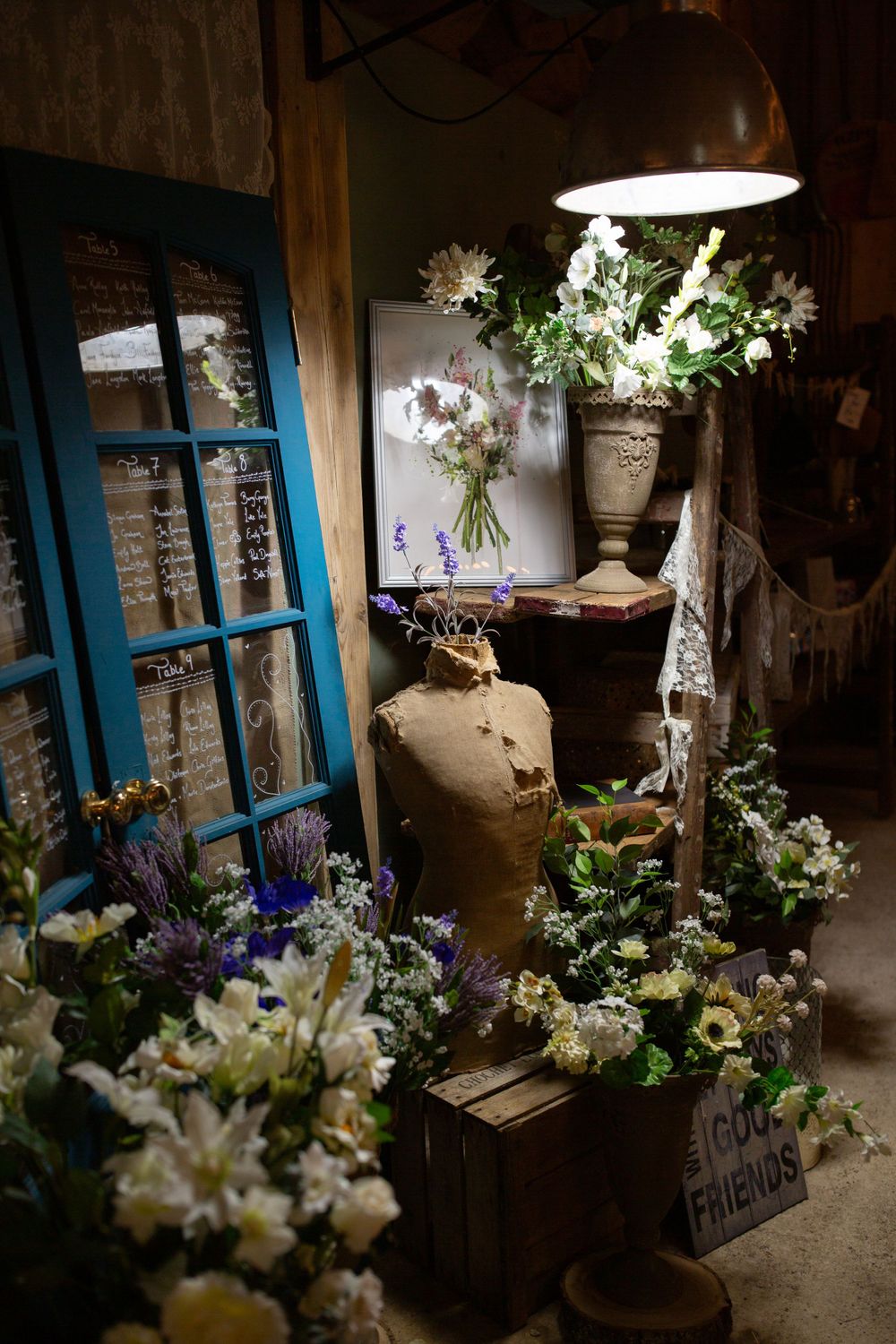 Rustic flower shop corner with blue window frame, vintage vase, and fresh wildflower arrangements.
