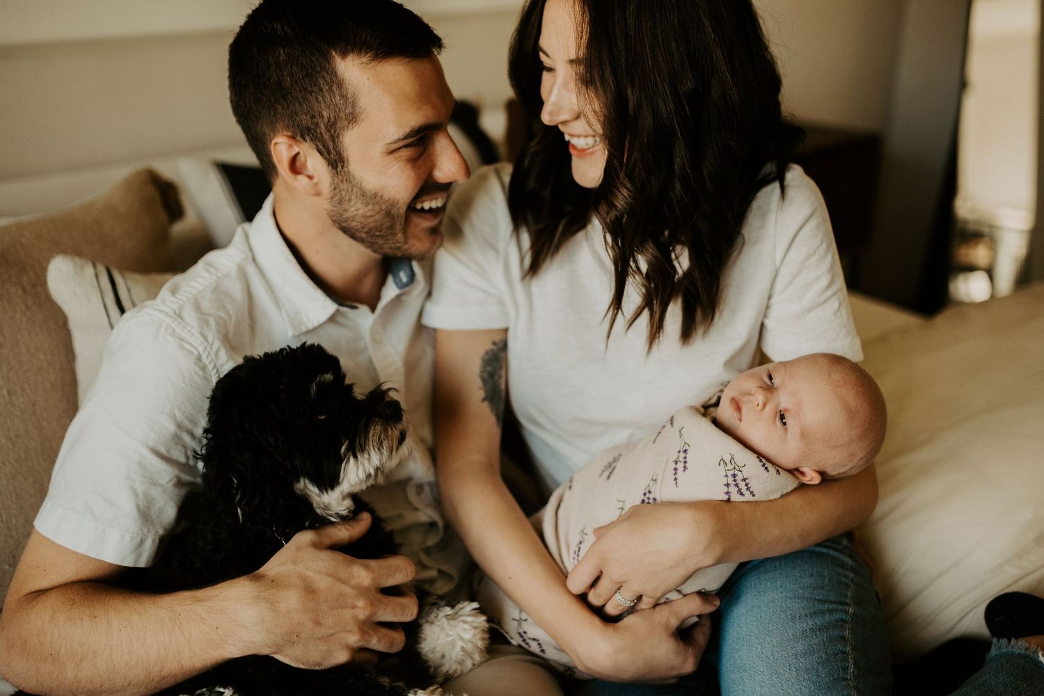 Family newborn photoshoot posing with dog in their home.
