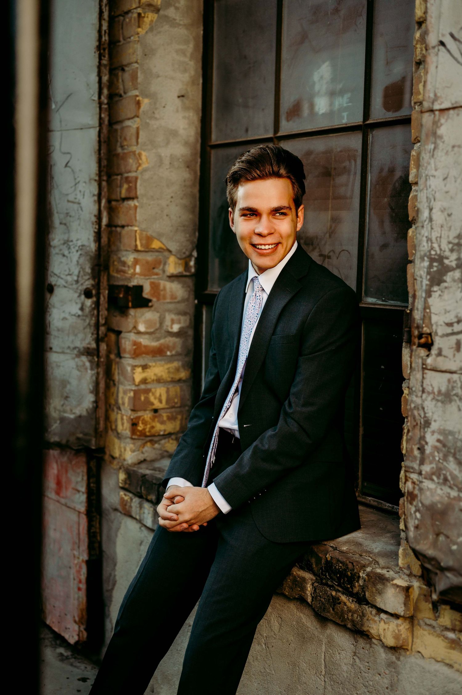 Stylish formal portraits against industrial brick wall background.