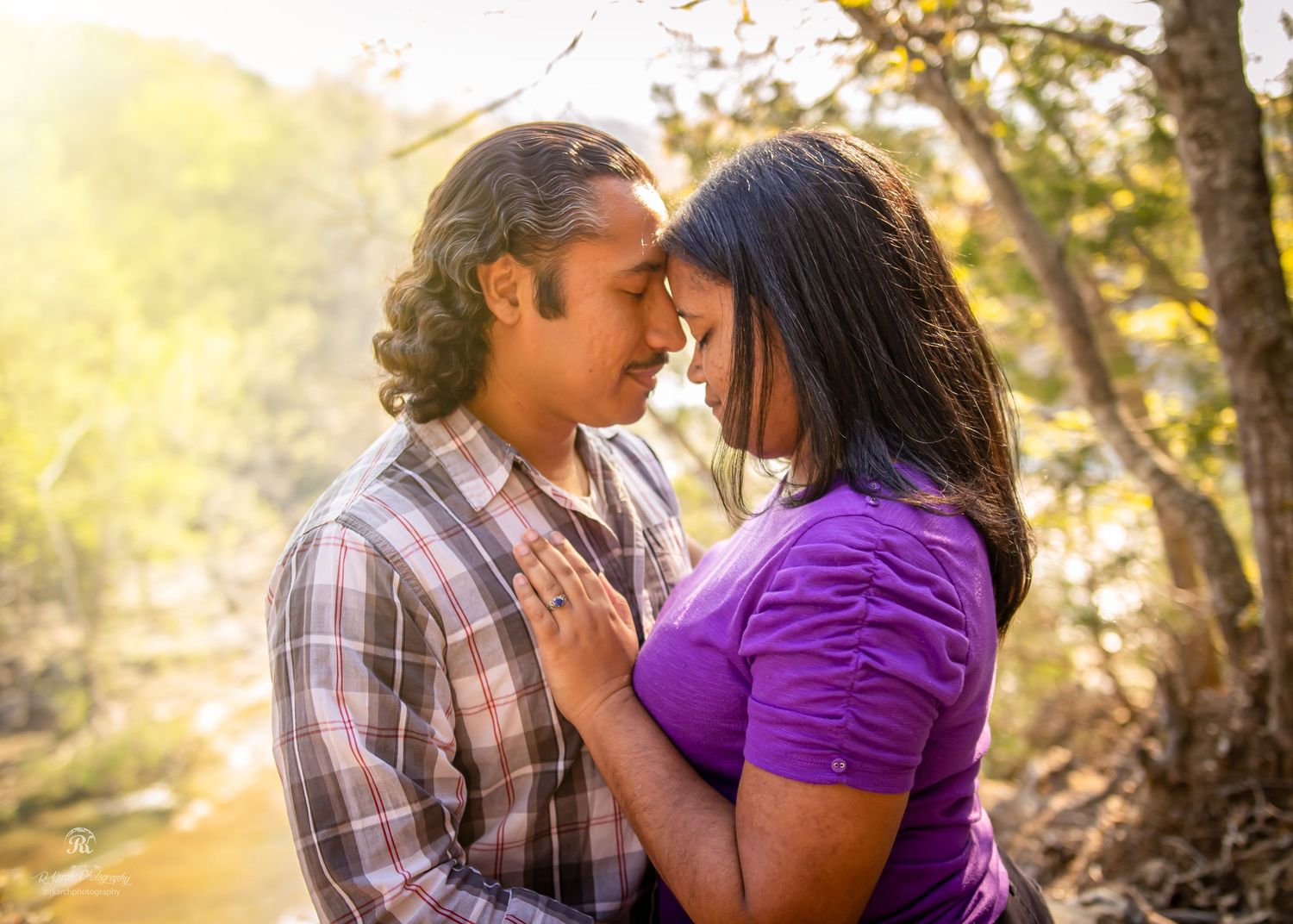 Romantic couple shares intimate moment in golden sunlit forest setting.