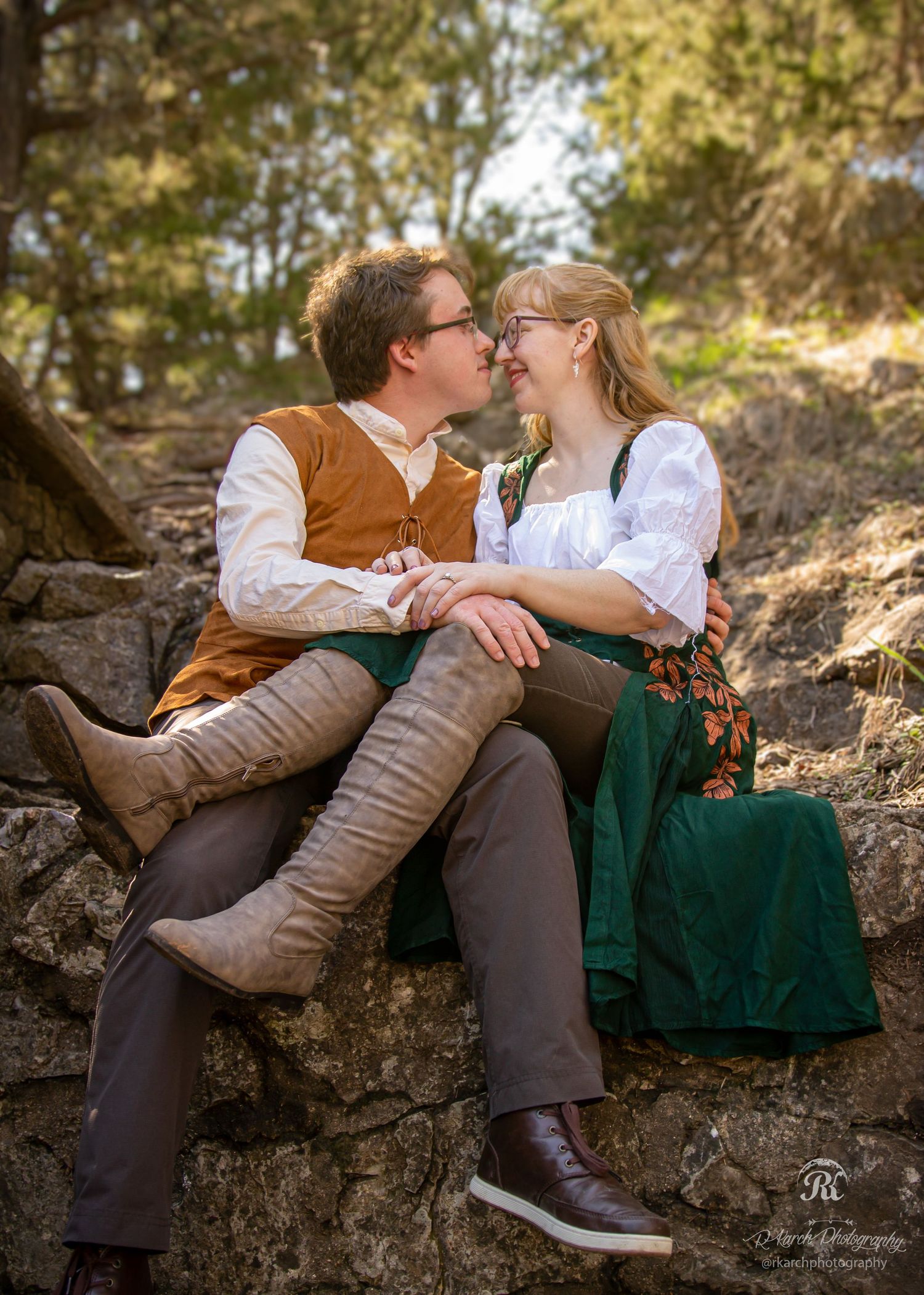 Couple in vintage-inspired clothing share an intimate moment on rocky terrain.