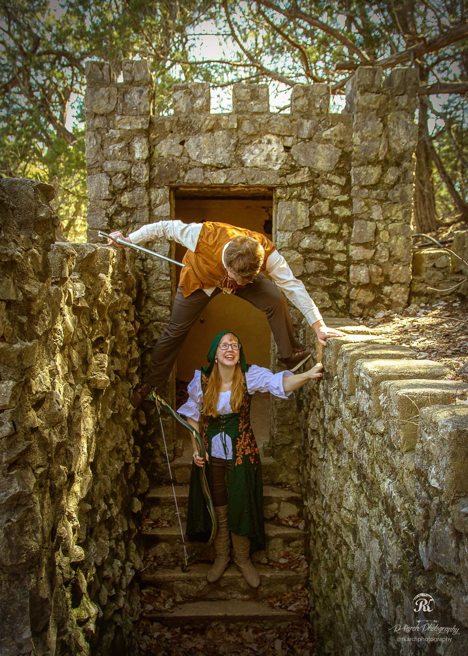Playful scene at stone castle ruins with two people posing on ancient steps.