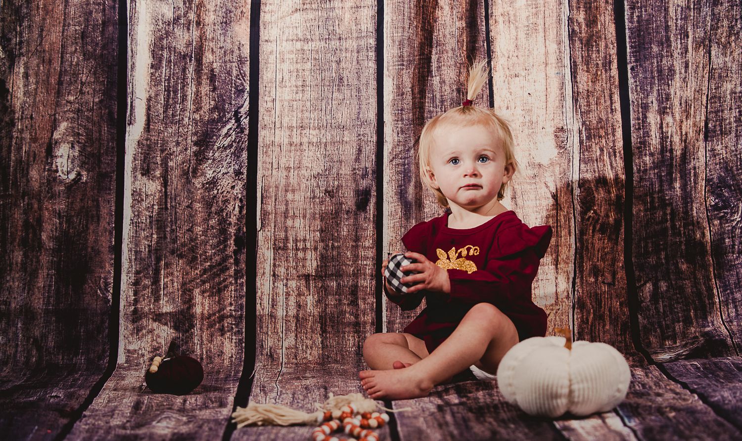 Fall themed portrait session with white pumpkins and rustic wooden backdrop.