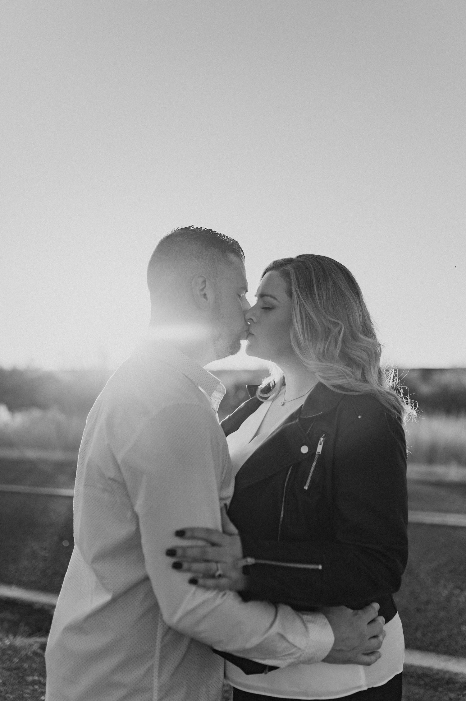 A silhouetted couple shares an intimate kiss at sunset.