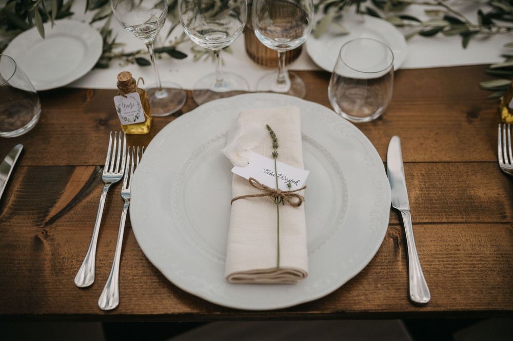 Close up of minimalist table setting with white plates and folded napkins on wooden surface.