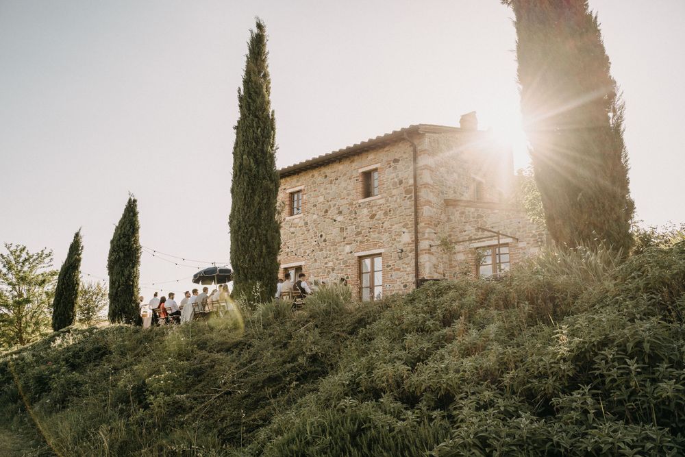 Stone villa in Tuscany at sunset with cypress trees creating dramatic silhouettes.