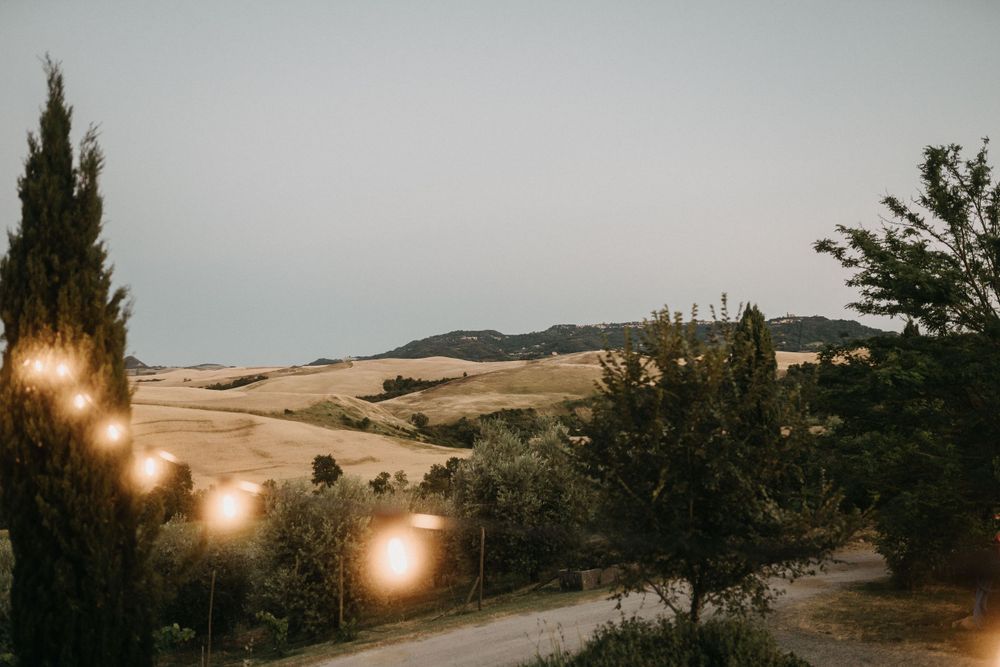 Panoramic view of Tuscan countryside with golden light and villa silhouette.