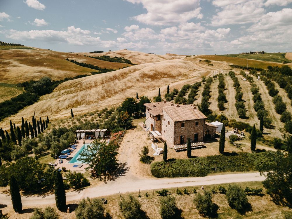 Aerial view of Italian countryside estate with rows of cypress trees and Mediterranean architecture.