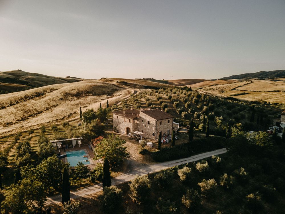Scenic landscape of hillside villa surrounded by olive groves and cypress-lined pathways.
