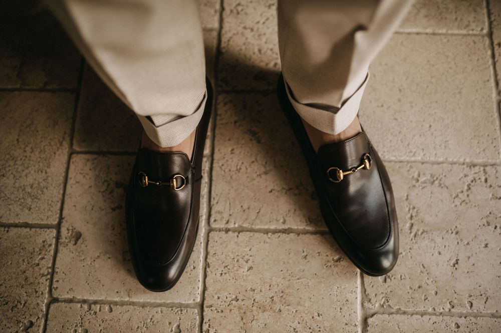 Close up of polished black dress shoes on stone tile floor.
