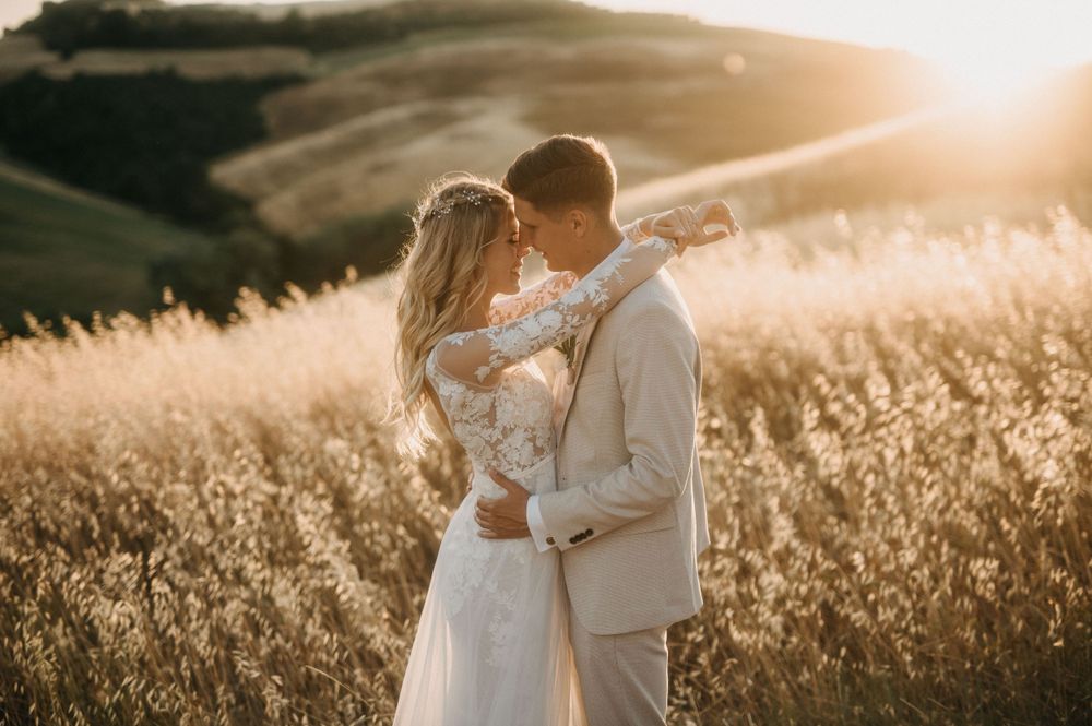 Intimate wedding portrait of couple in warm sunset light with Tuscan landscape backdrop.