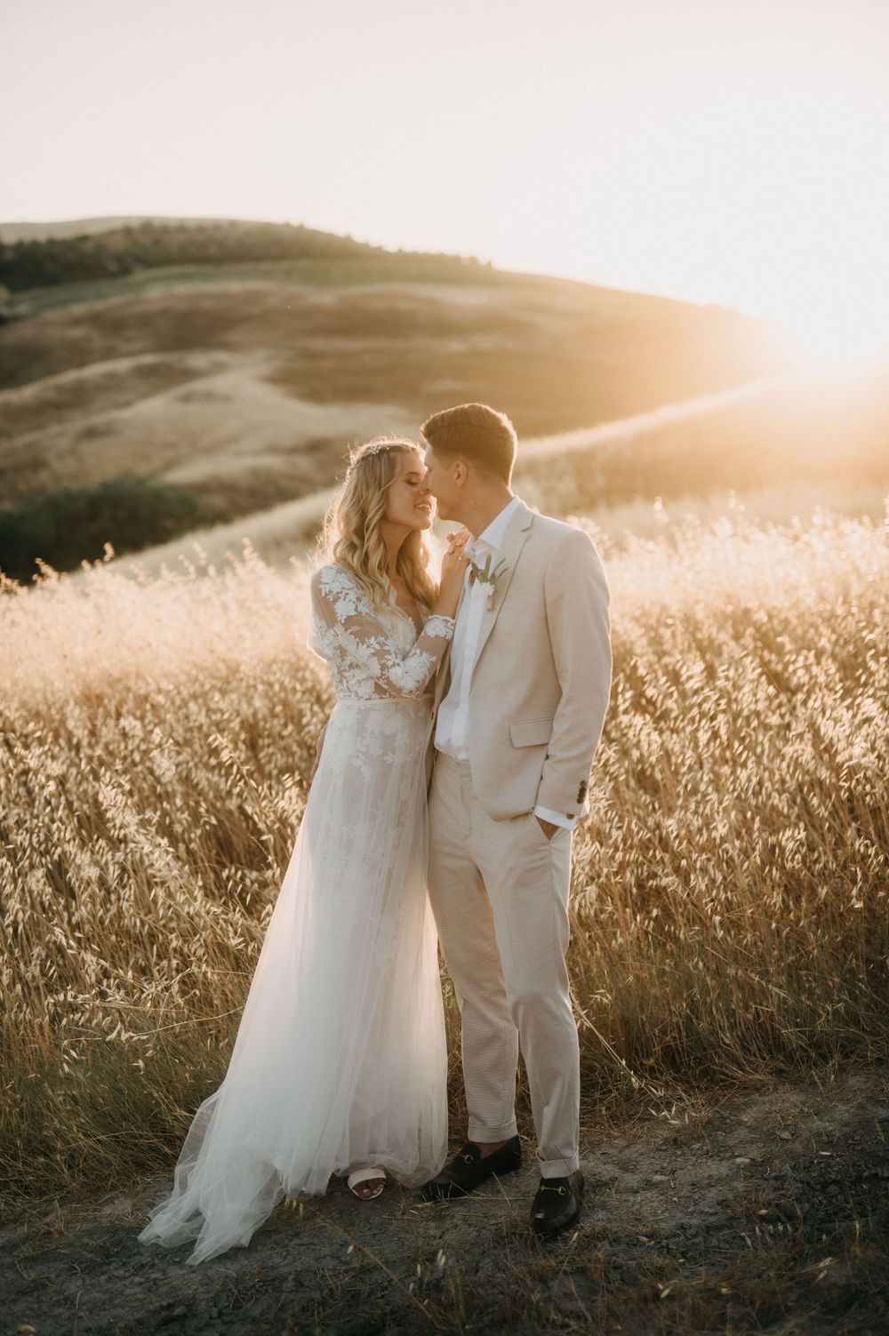 Romantic wedding kiss captured during golden hour in rustic Italian countryside.
