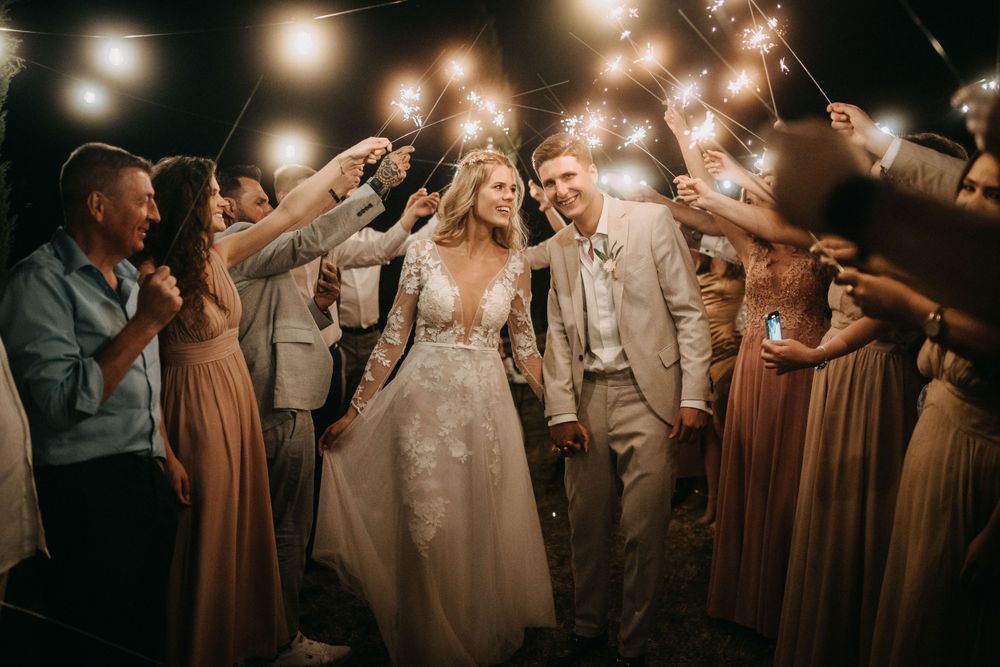 Wedding party celebrates with sparklers creating a festive nighttime atmosphere.