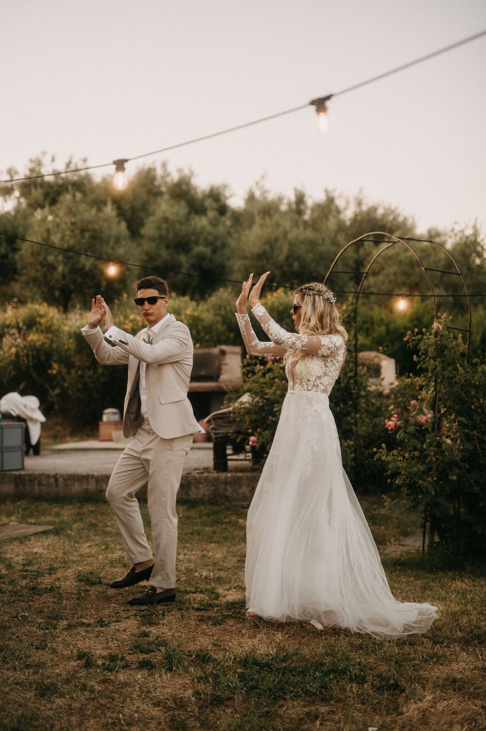 Couple dancing playfully in garden setting during wedding celebration.