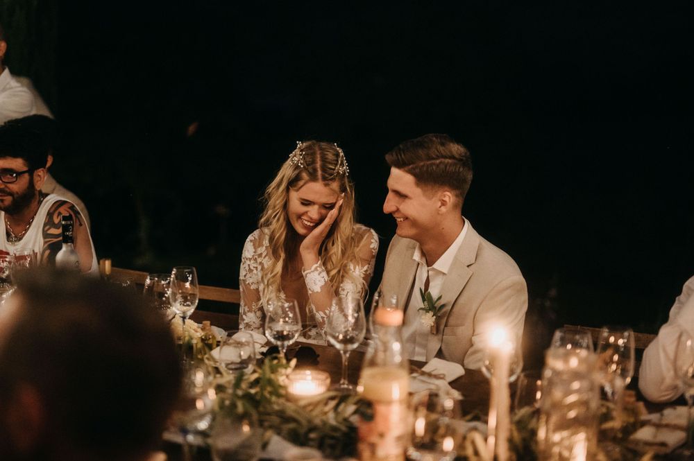 Intimate candlelit dinner scene at outdoor wedding reception.