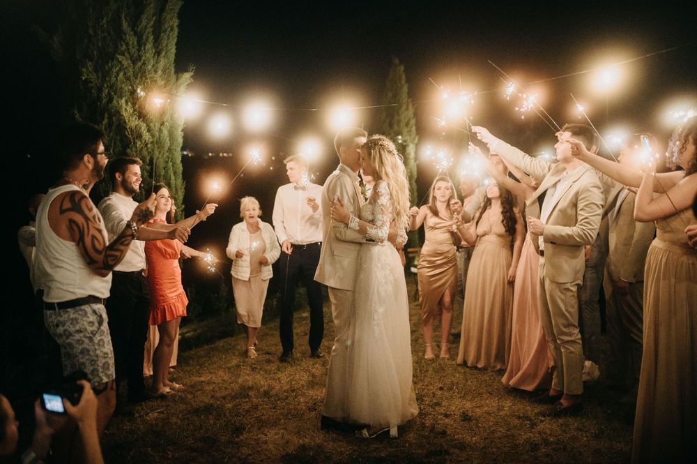 Wedding celebration under string lights with guests dancing in circle at night.